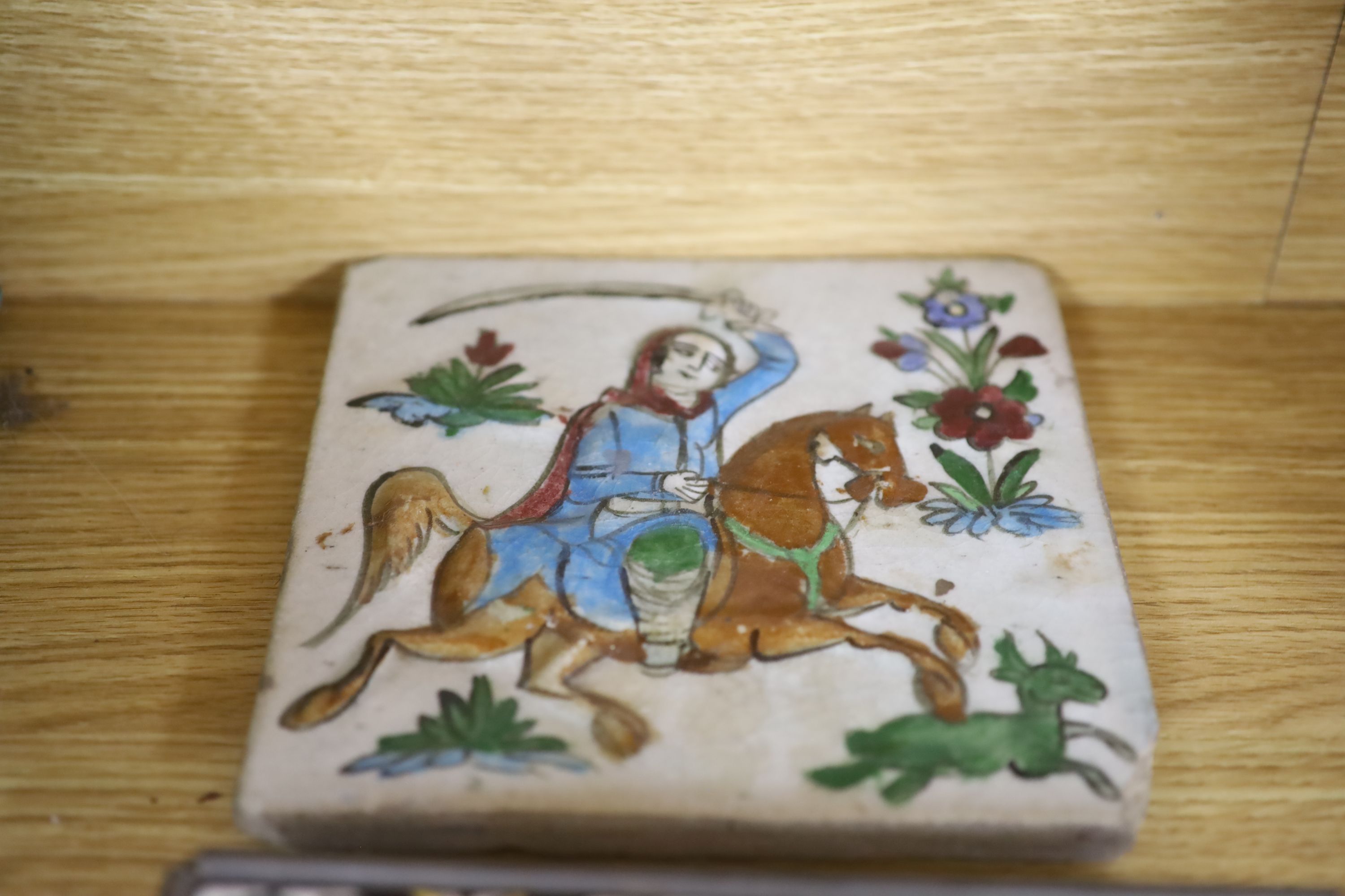 A framed glazed earthenware plaque, a tin glazed tile and one other